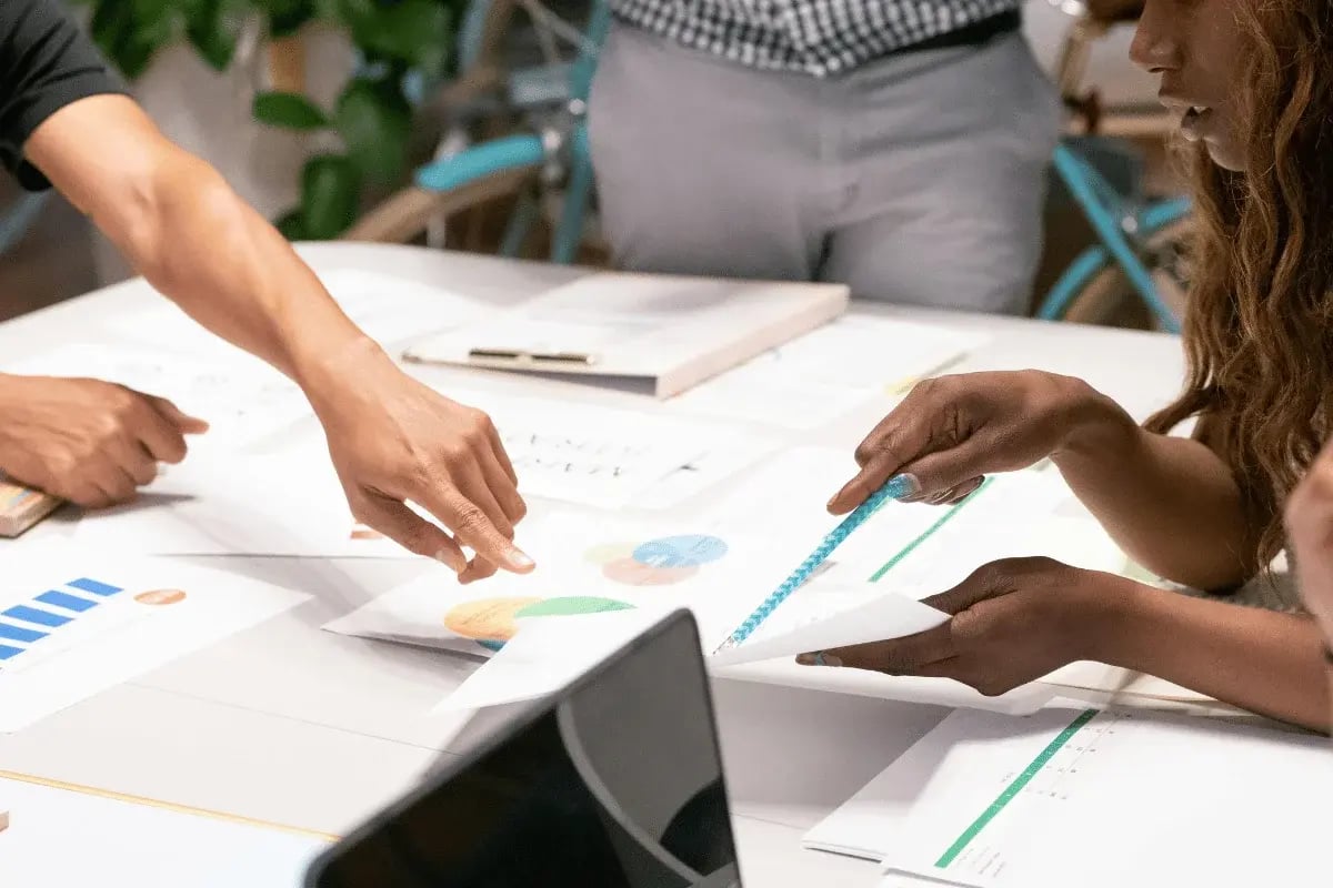Close-up of hands analyzing data reports with charts at a business meeting.
