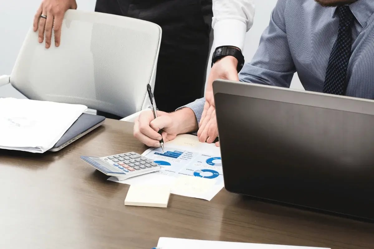 Financial advisors reviewing charts and graphs with a calculator and laptop.