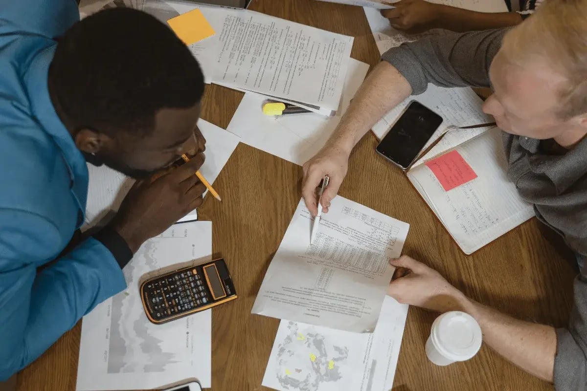 Team analyzing printed documents and charts during a meeting.