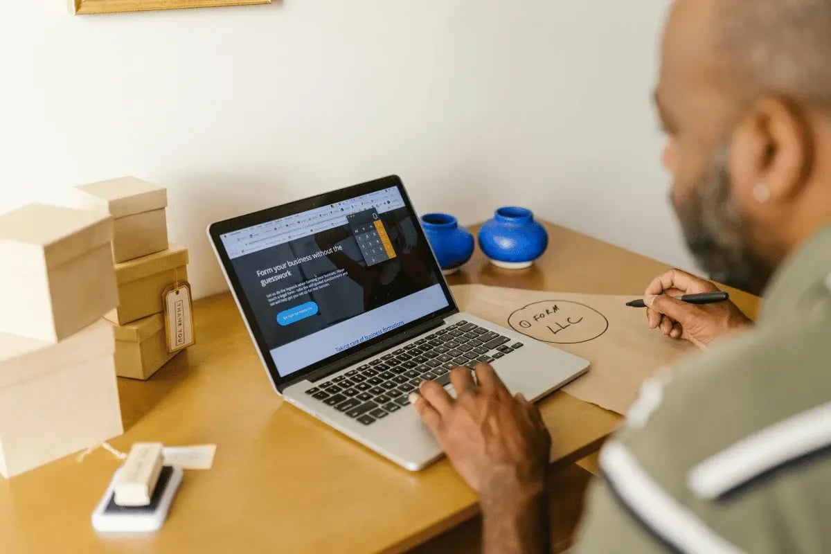Laptop showing LLC registration website as man prepares to start business.