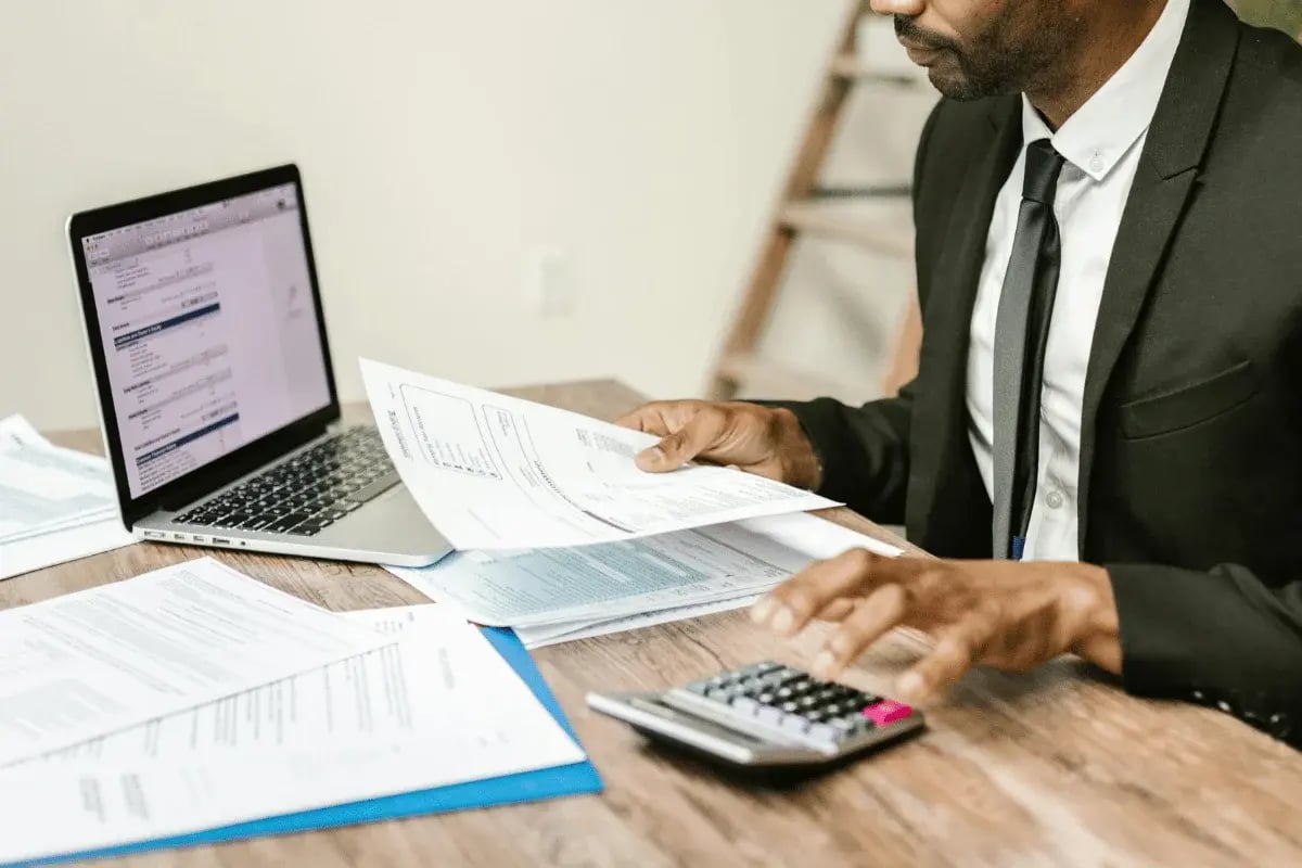 Man calculating numbers on a financial report at desk.
