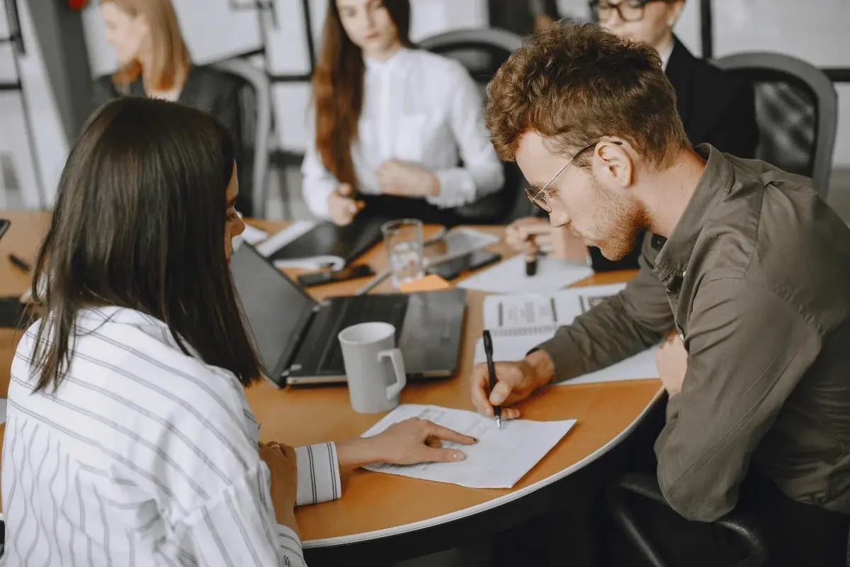 Office team focused on document analysis and taking notes during a meeting.