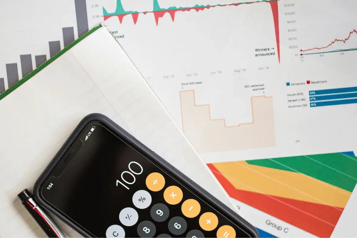 Mobile calculator on notebook with colorful data charts.