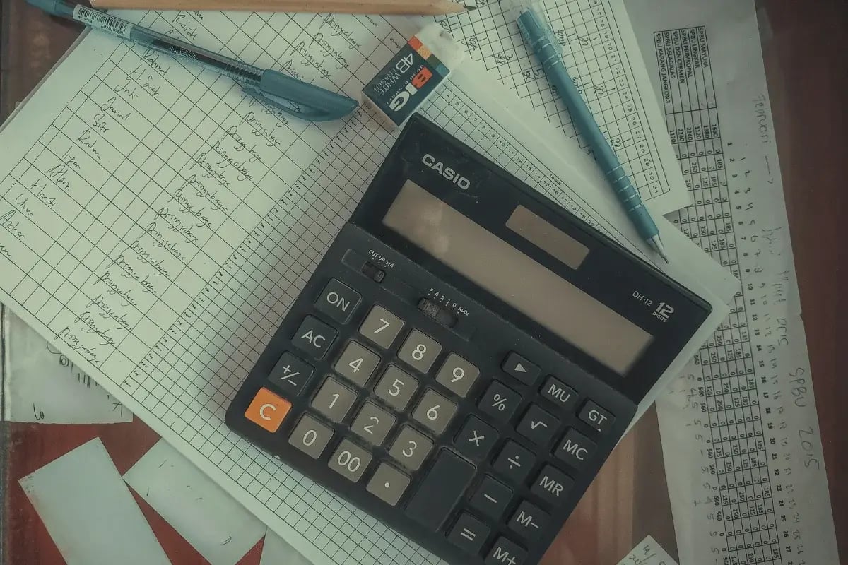 Black Casio calculator on graph paper with handwritten accounting notes.