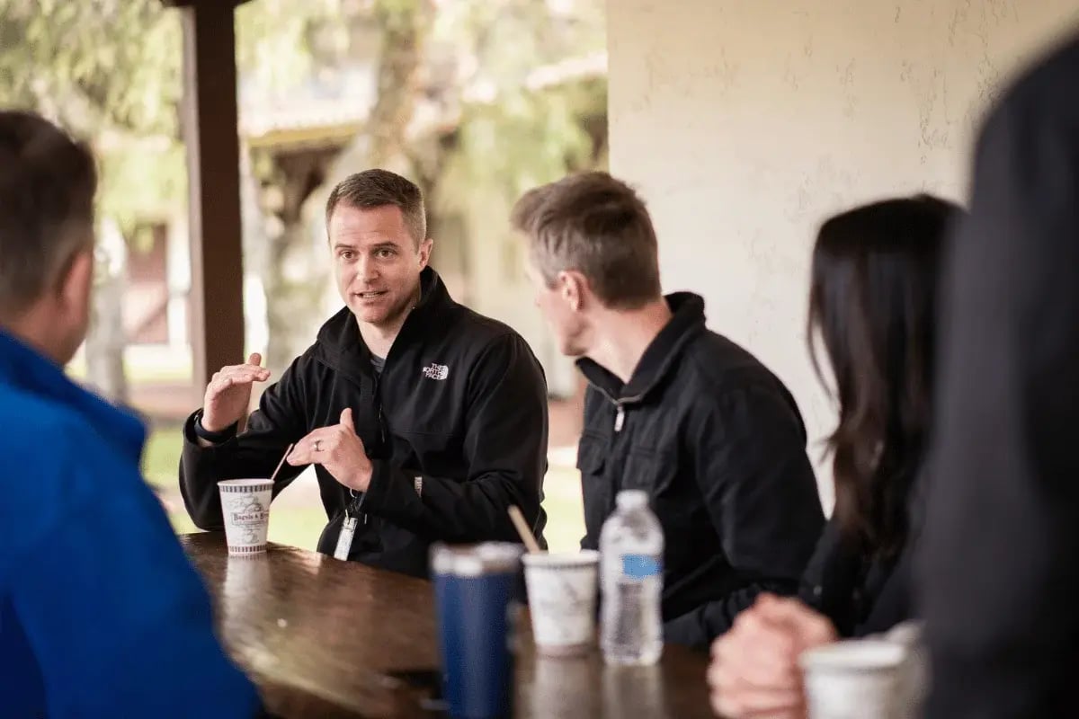 A man explaining something to a group during an outdoor meeting.