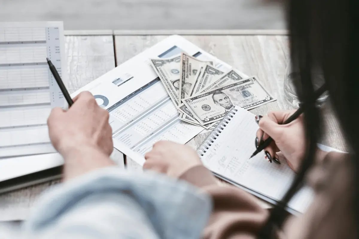 People reviewing financial charts and taking notes with cash on the table.